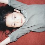 Child lying on a red surface wearing JEJEUNOSITY kidswear